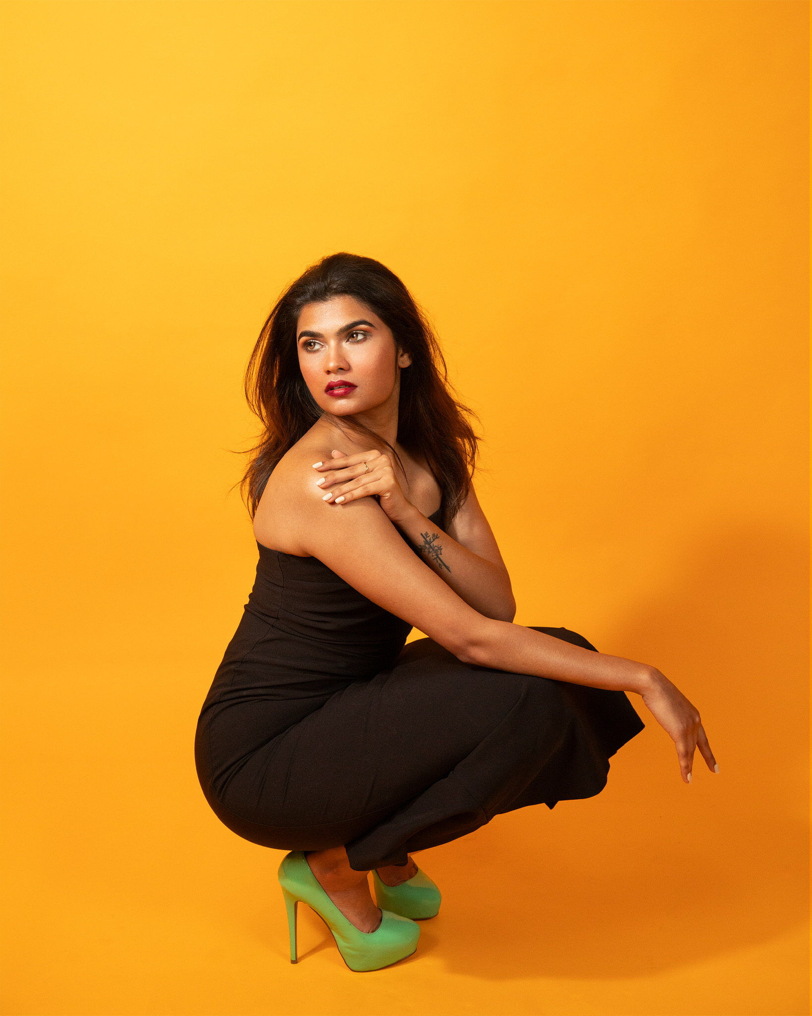 Studio portrait — yellow backdrop crouching
