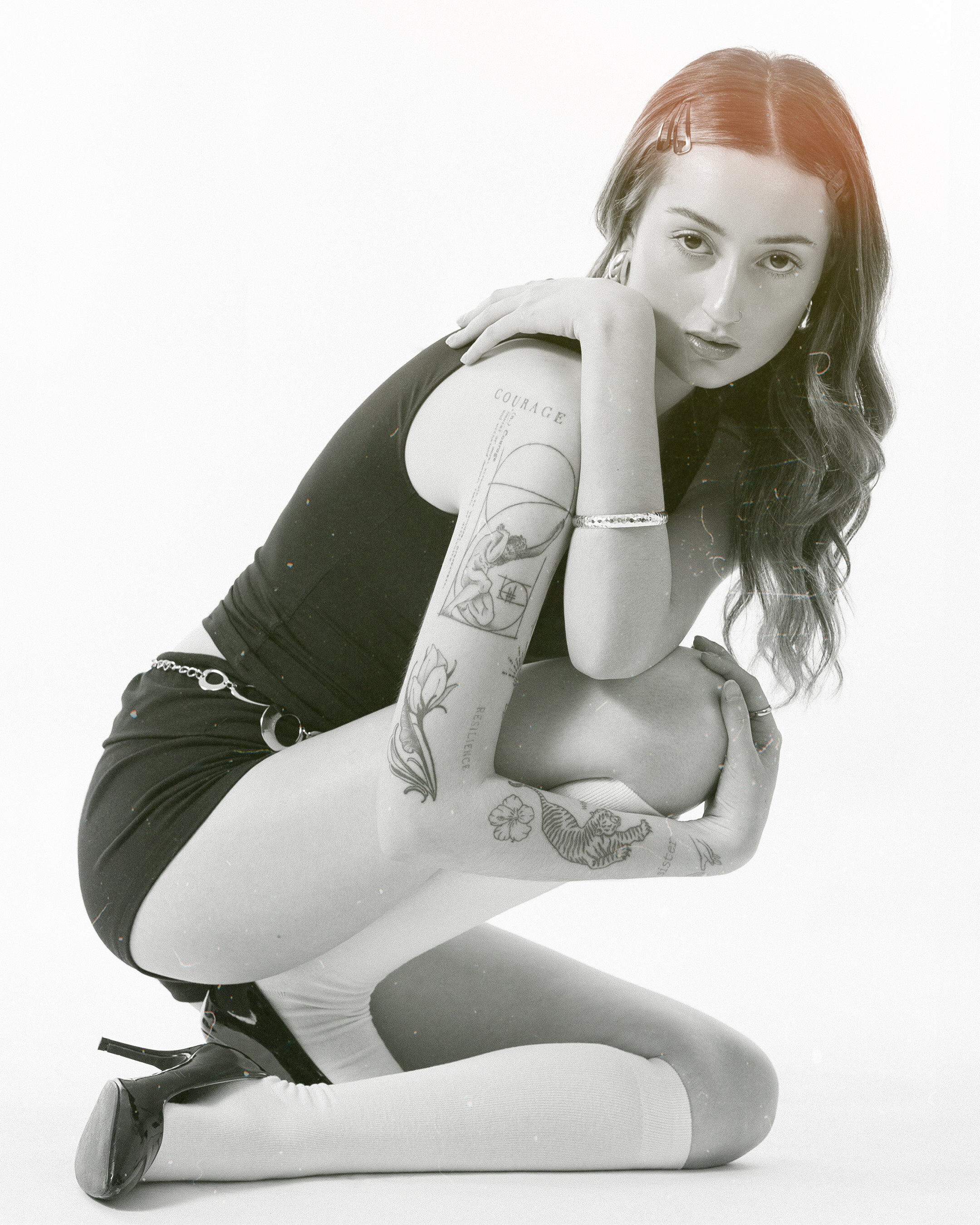 Film grain editorial — crouching tattoo portrait