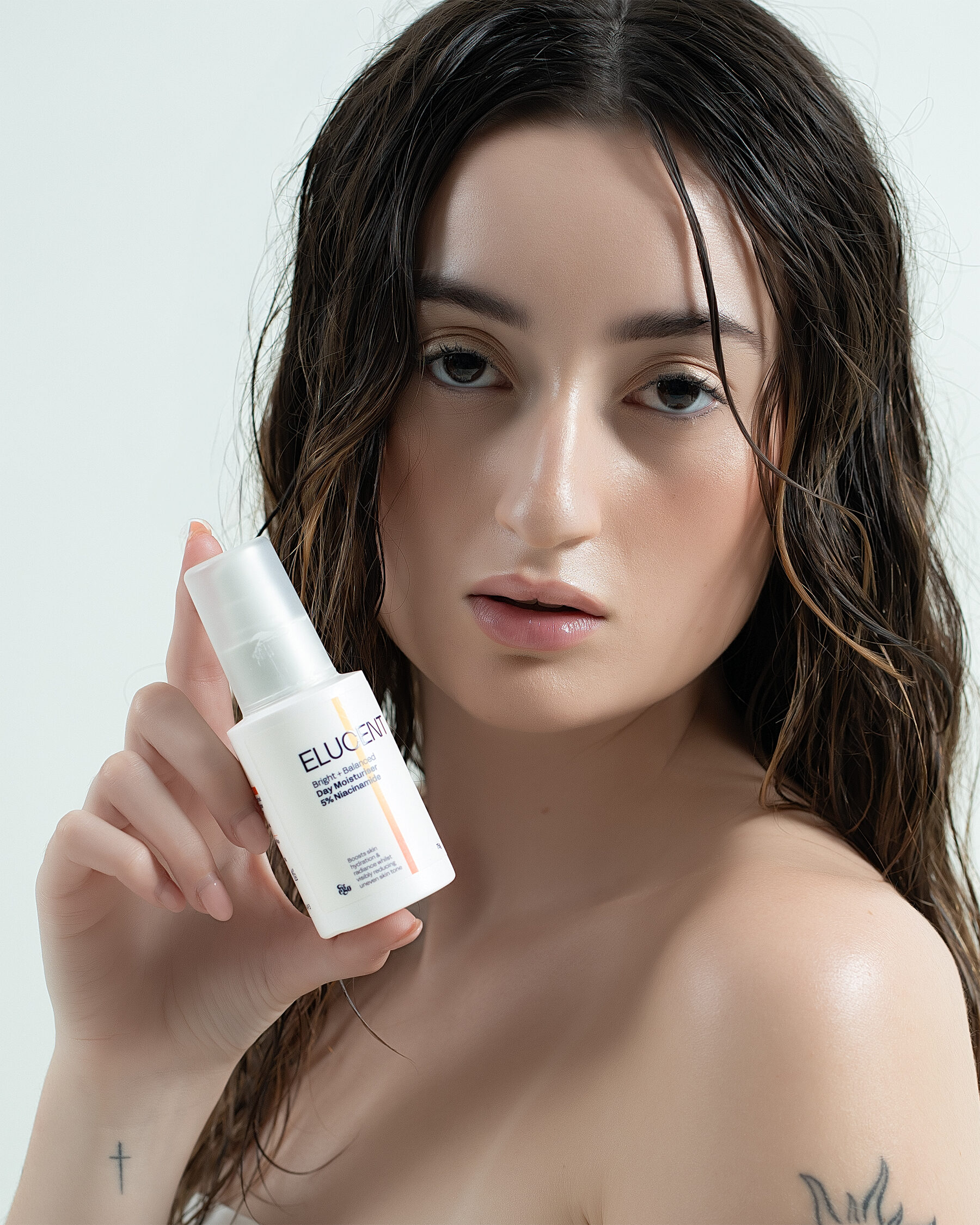 Elucent Day Moisturiser — editorial direct gaze with product