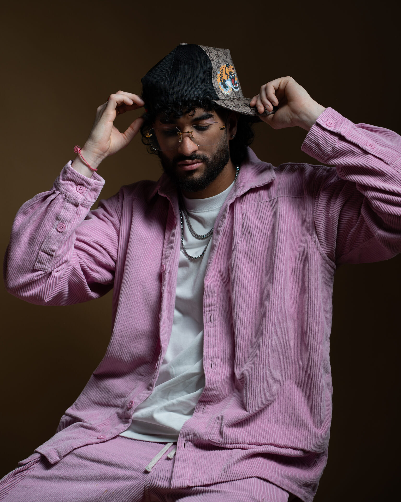 Artist editorial — adjusting cap seated dark backdrop